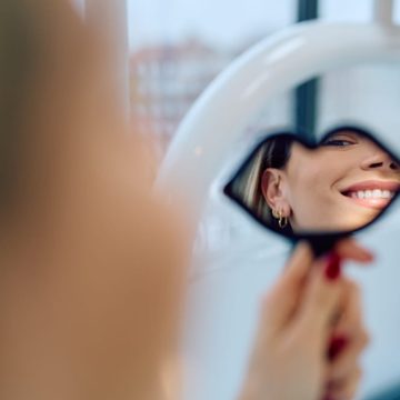 Une jeune femme admire son sourire après un traitement en esthétique dentaire